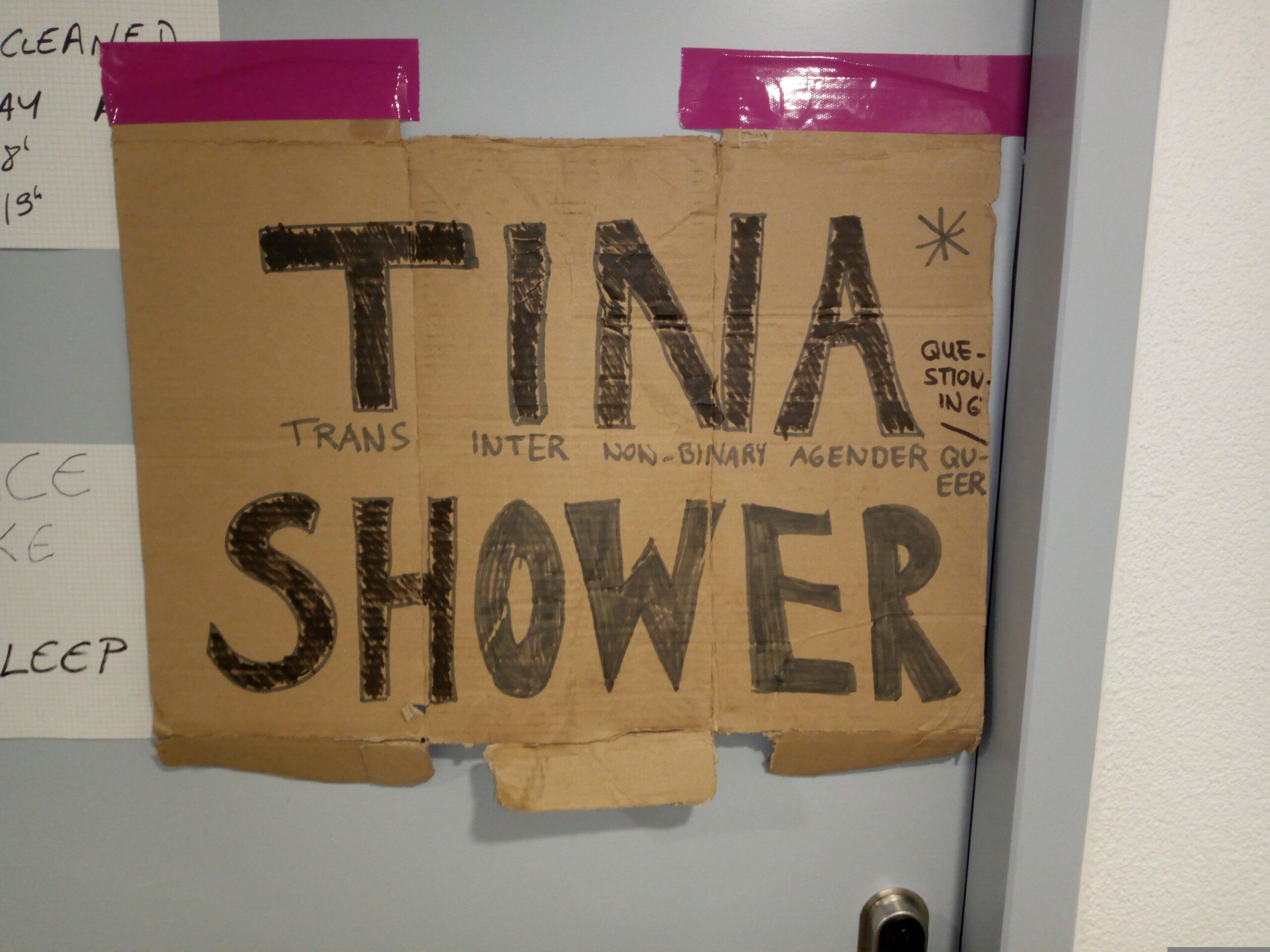 Ein Türschild, auf dem eine Dusche als "Trans Inter Nonbinary Agender Shower" ausgeschrieben ist.